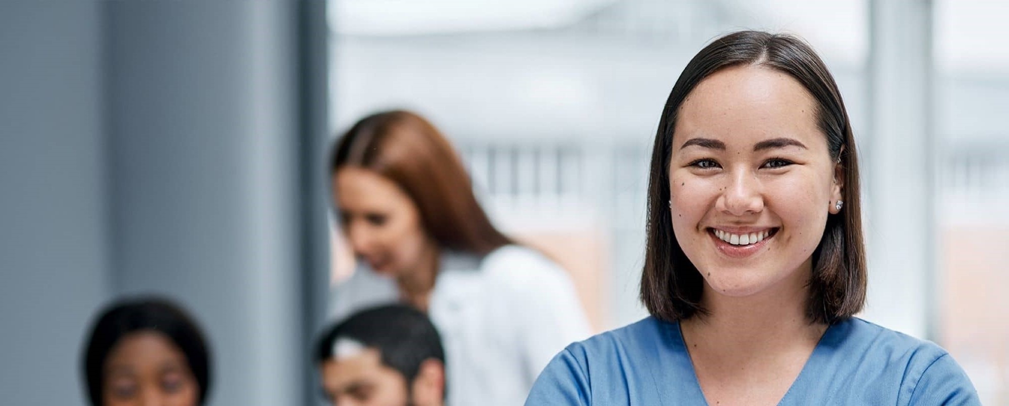 3 strike nurses smiling wearing blue scrubs